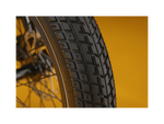 Close up of an ebike tire tread pattern against a gold background.