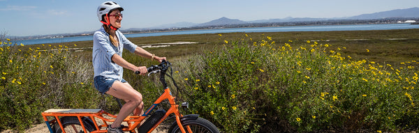 A woman rides a RadWagon along the coast.