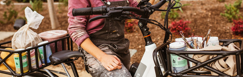 A person rides a Rad Power Bike loaded with pottery supplies.