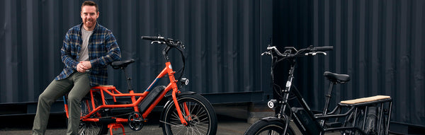 Mike Radenbaugh seated on the back of an orange RadWagon next to a black RadWagon.