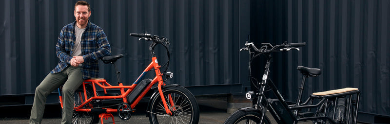 Mike Radenbaugh seated on the back of an orange RadWagon next to a black RadWagon.