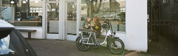 A woman and child eat donuts alongside a RadRunner Plus.