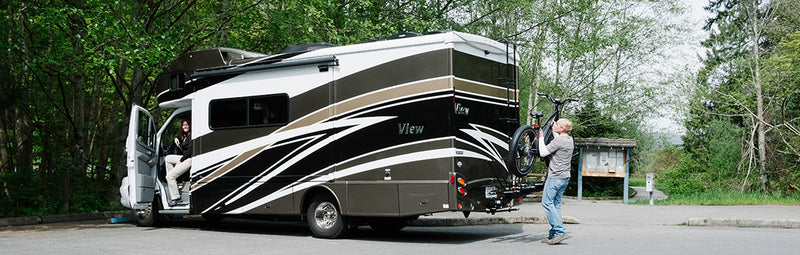 Man loads Rad ebike on the rack behind an RV.