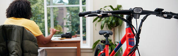 A college student studies while sitting next to a red RadMission electric metro bike