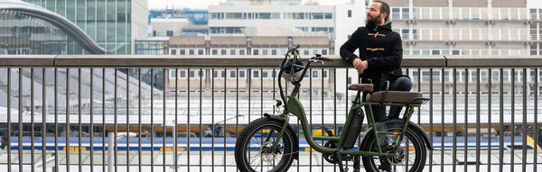 A man in fall attire rides a RadRunner electric utility bike amid a fall backdrop.