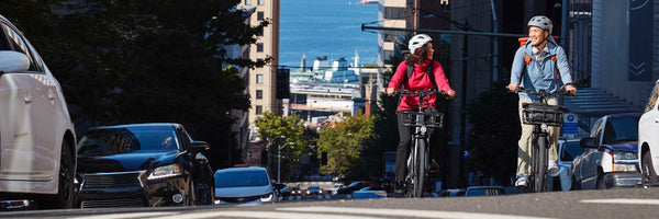 A man and woman ride their RadCity 5 Plus up a city hill.