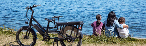 A mother sits with her children next to a RadWagon electric cargo bike.