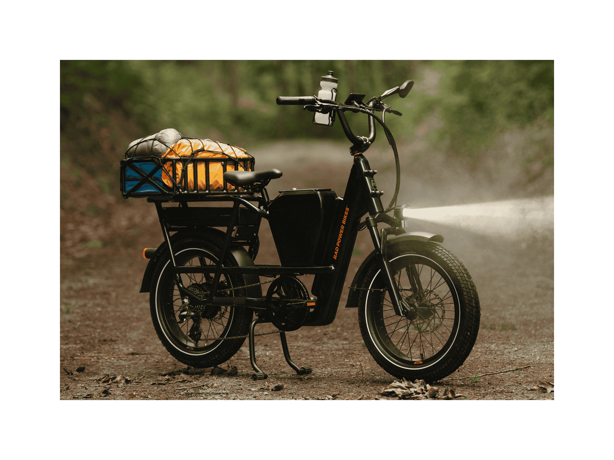 A emerald green ebike resting on its kickstand on a trail in a forest.