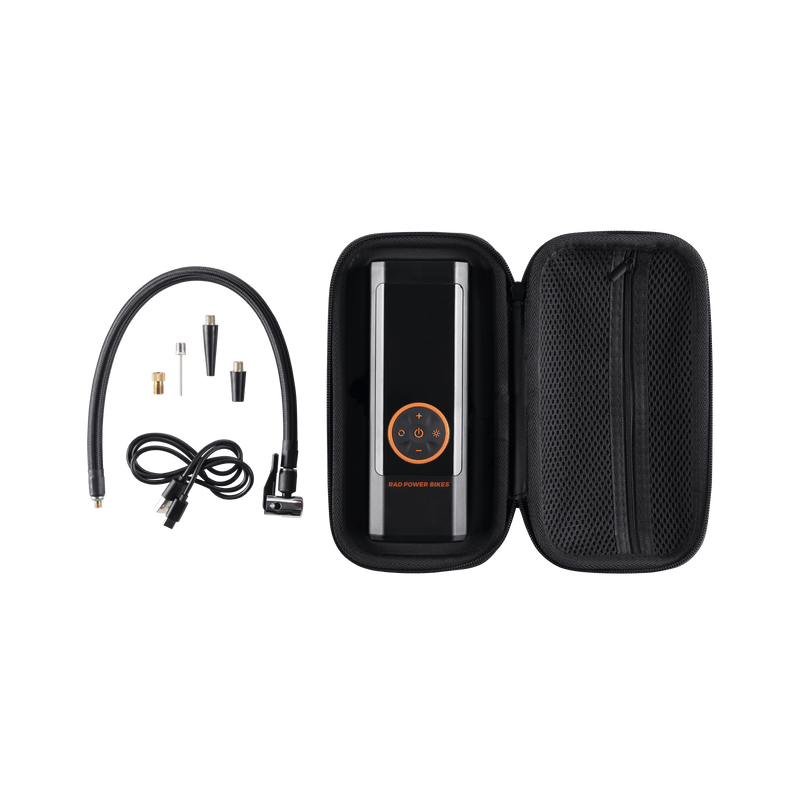 Rad Portable Tire Inflator in a black carrying case with mesh zip pocket and air hose with Q/R Schrader Head, USB-C charging cable, and four valve adaptors.