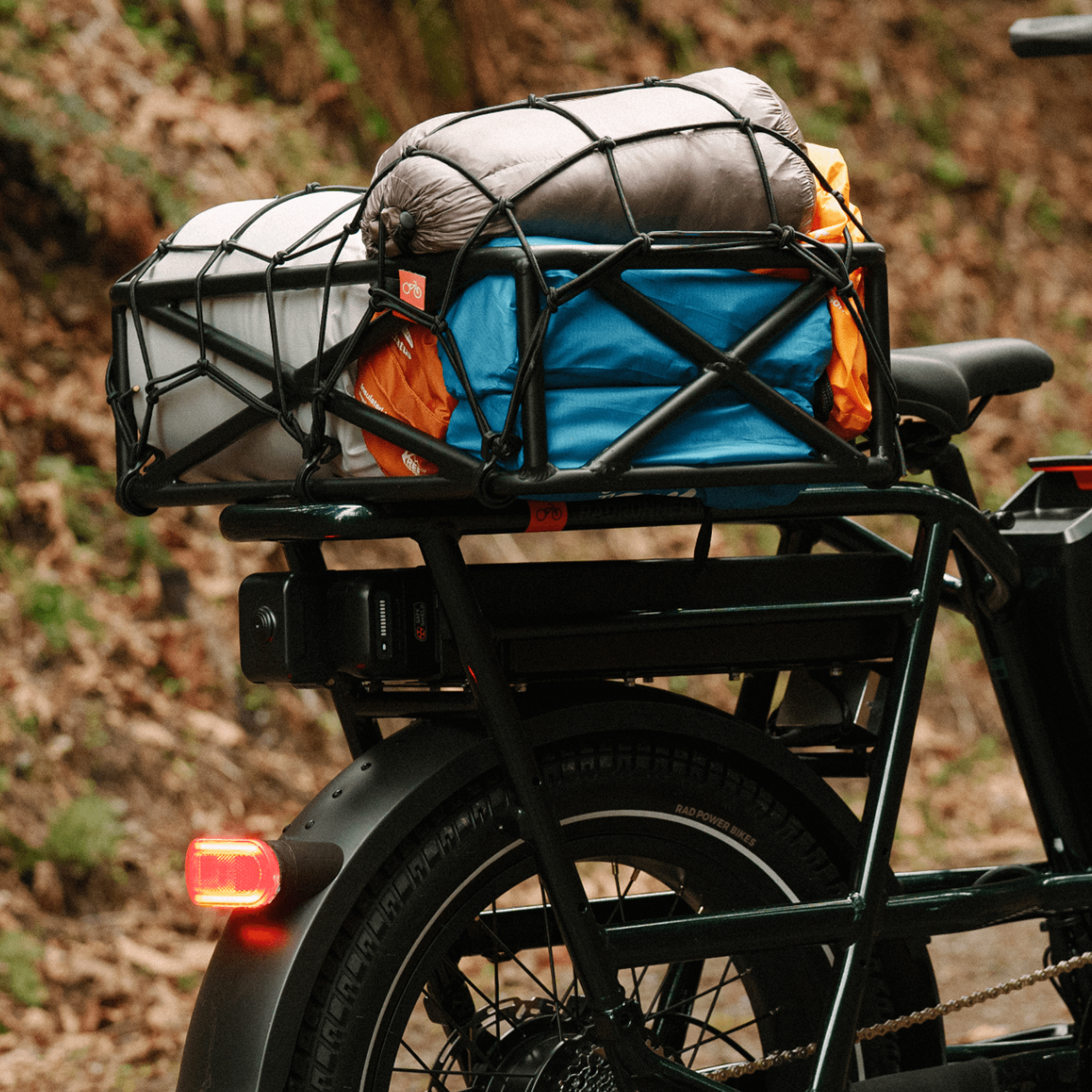 A RadRunner range extender installed on a green ebike which has a basket mounted on it holding camping gear. 