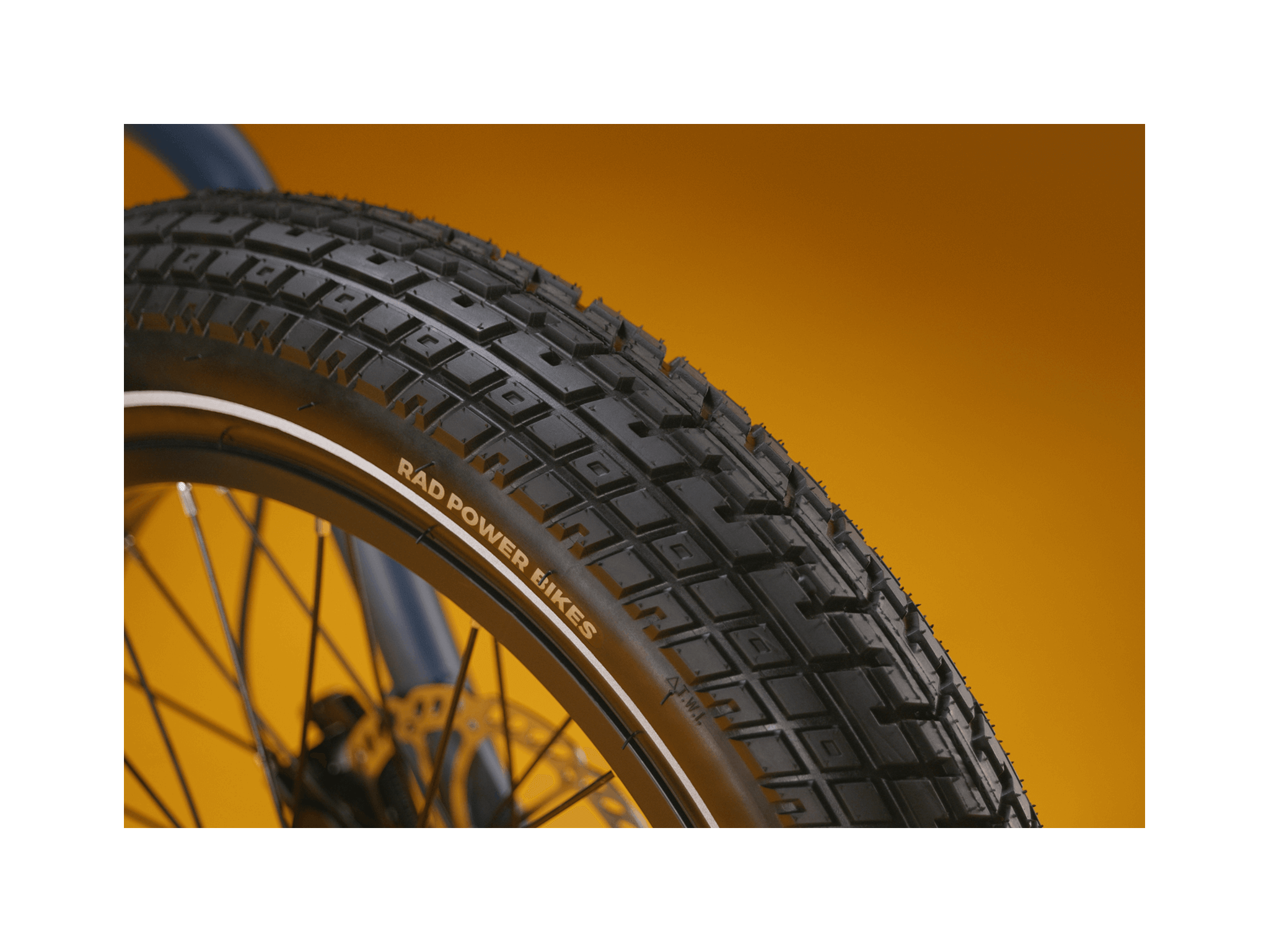 Close up of an ebike tire tread pattern against a gold background.