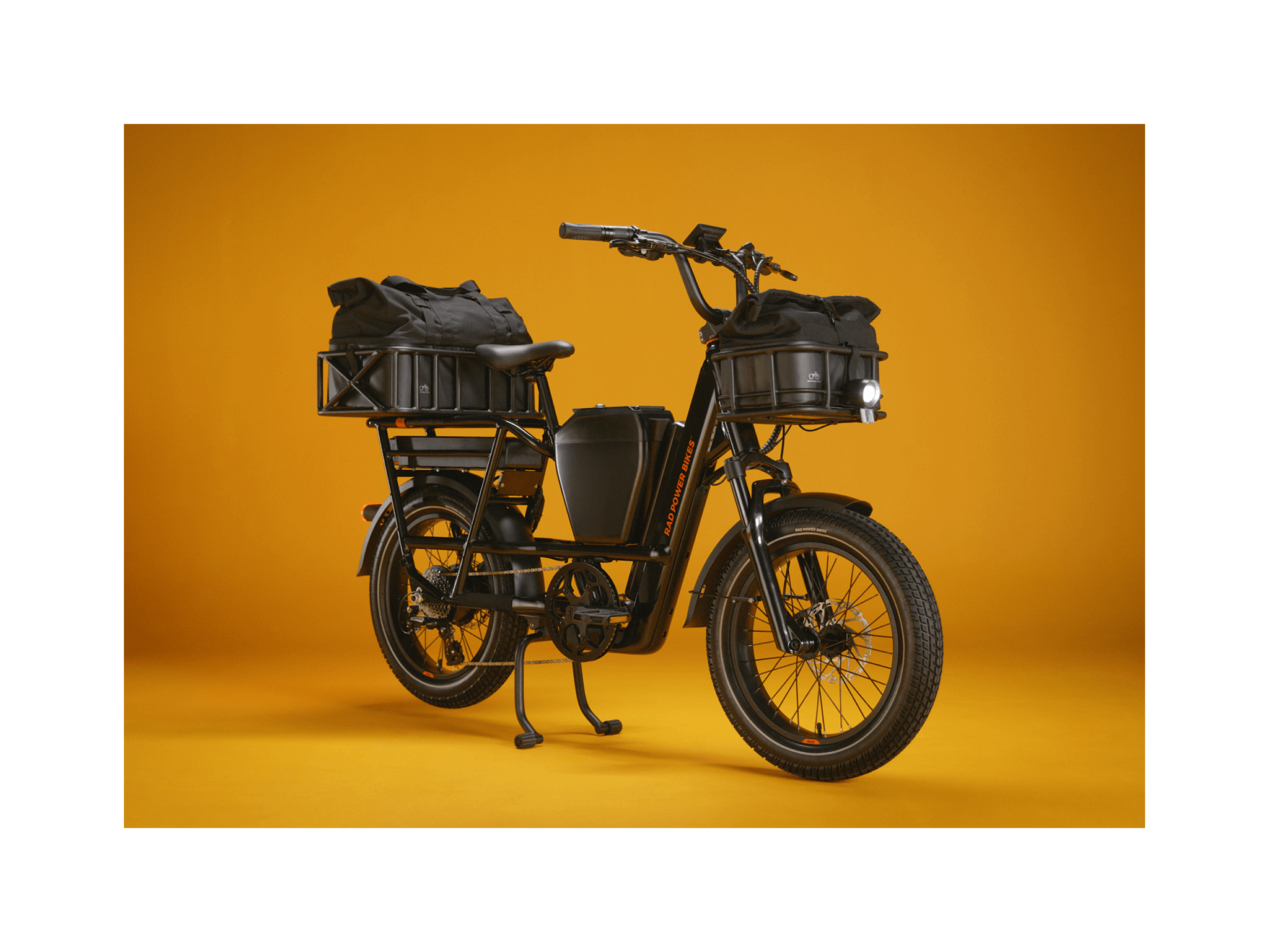 The right angle of a green RadRunner Max electric cargo utility bike with front and rear baskets, a center storage console, range extender, and an illuminated headlight. 
