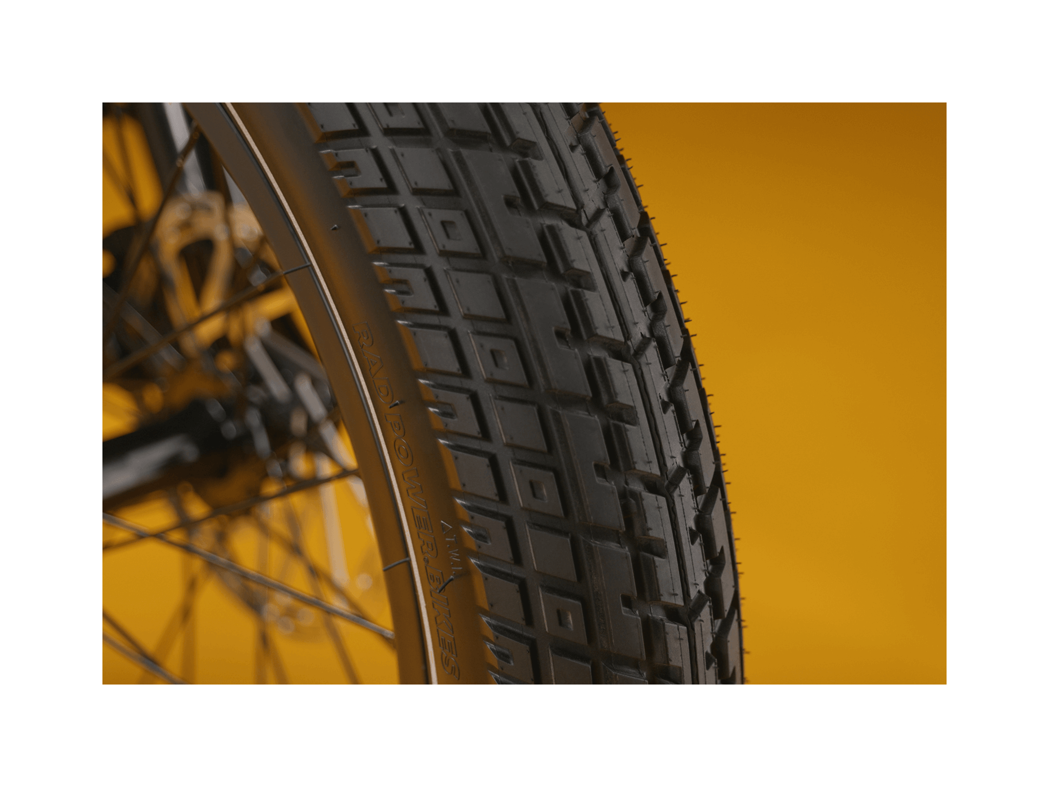 Close up of an ebike tire tread pattern against a gold background.