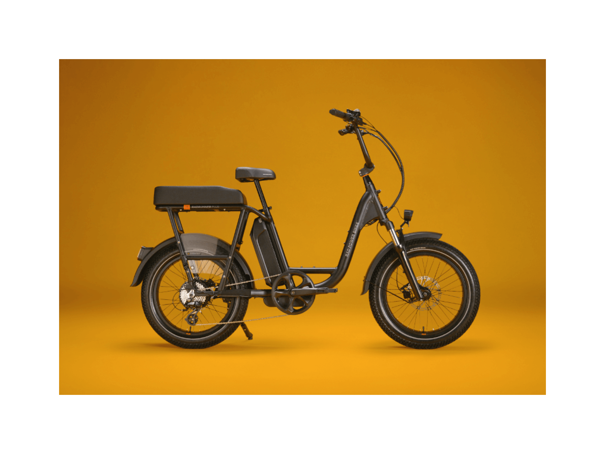 A matte black electric bike with a black passenger package against a gold background. 