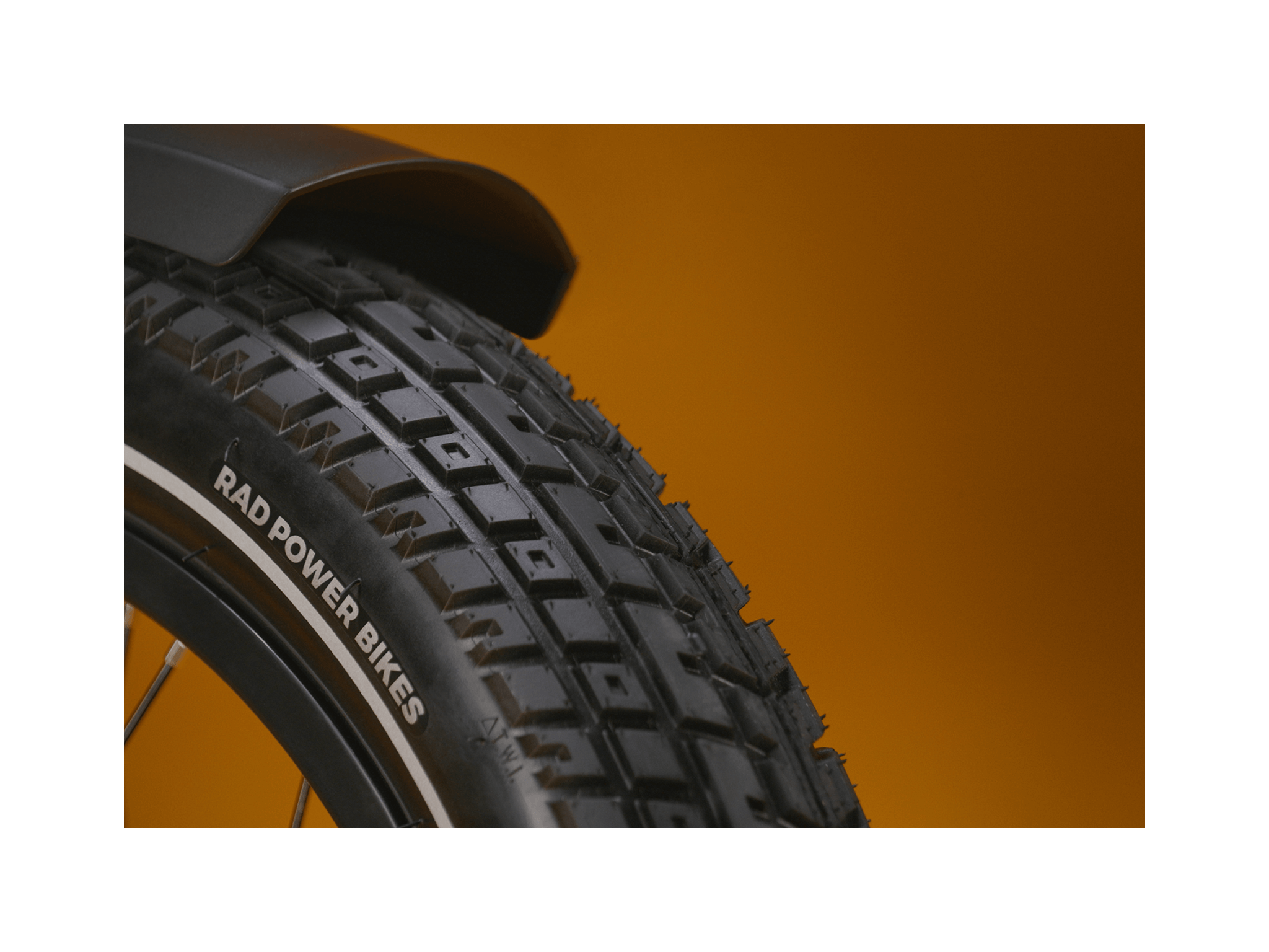 Close up of an ebike tire tread pattern against a gold background.
