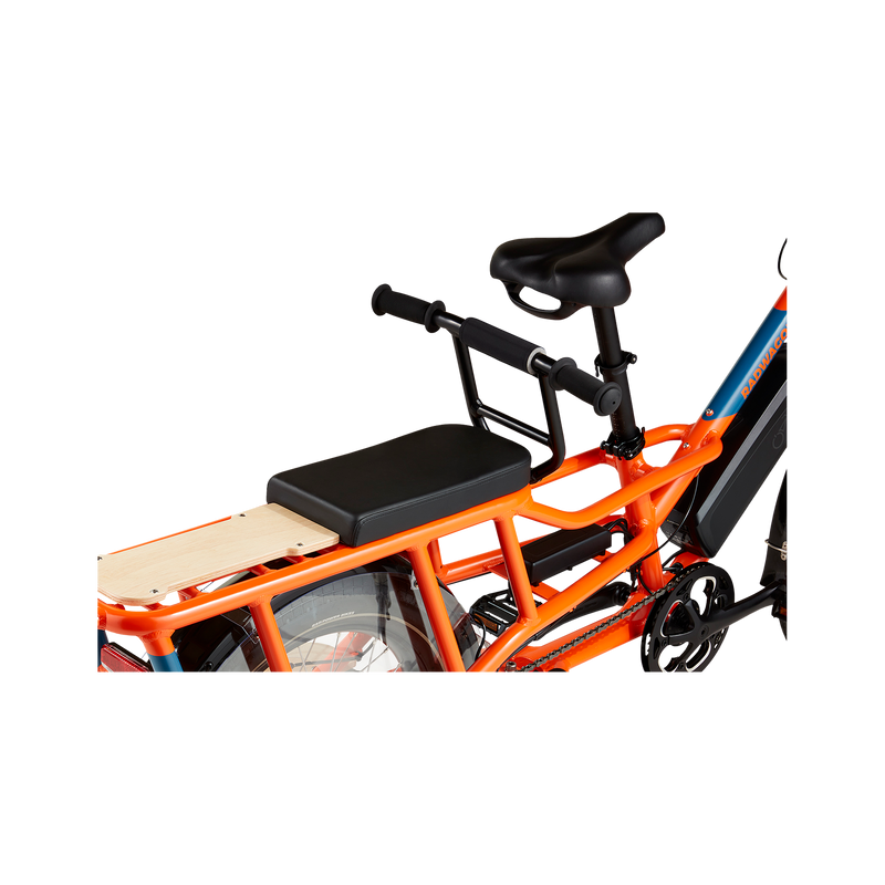 A close-up of a matte black Deckhand handlebar mounted in front of a Deckpad seat on the back of an orange RadWagon, right behind the saddle