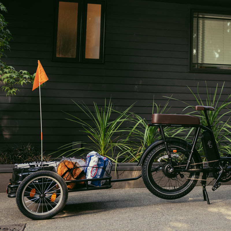 Rad Trailer loaded with barbeque supplies attached to an electric bike parked in front of a house.